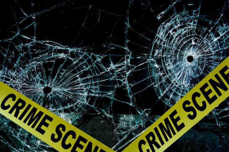 crime-scene-tape-across-glass-with-two-bullet-holes-768x512